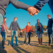 Mensen staan in een kring en houden elkaars hand vast. 