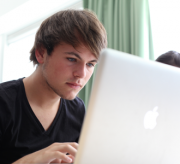 Een jongen werkt op een laptop.